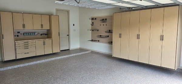 Empty room with beige cabinets, wall shelves, and gray carpet under fluorescent lights