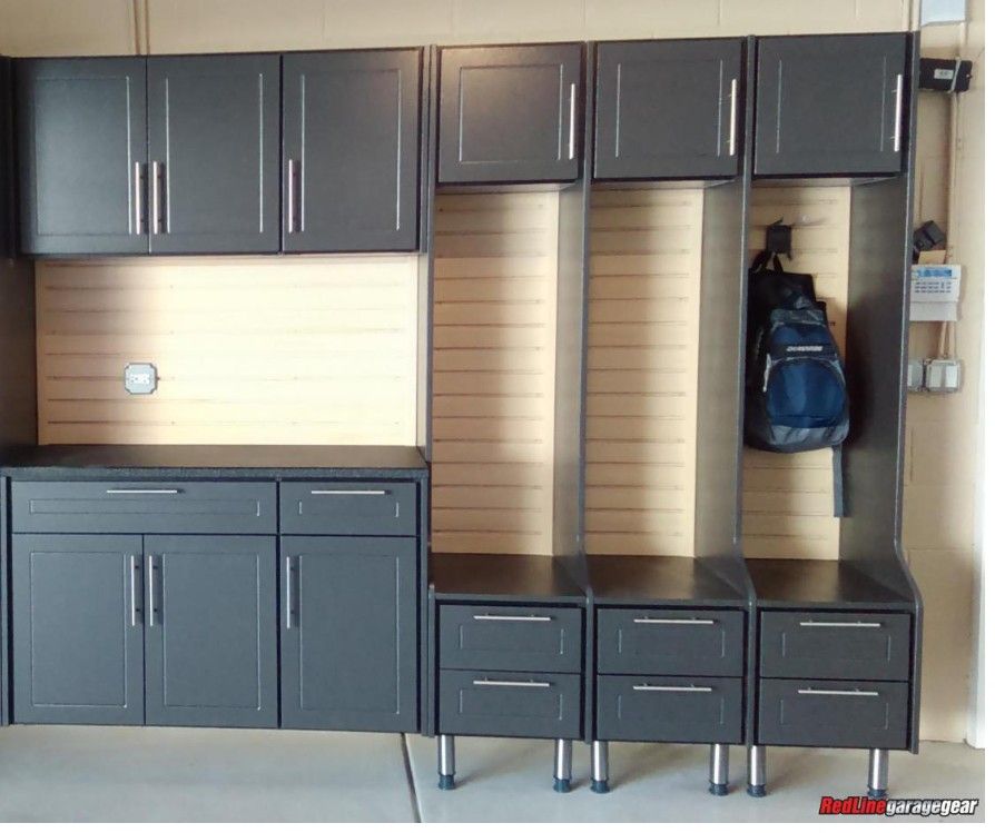 Dark gray garage storage cabinets and drawers with a workbench and hanging backpack on the right