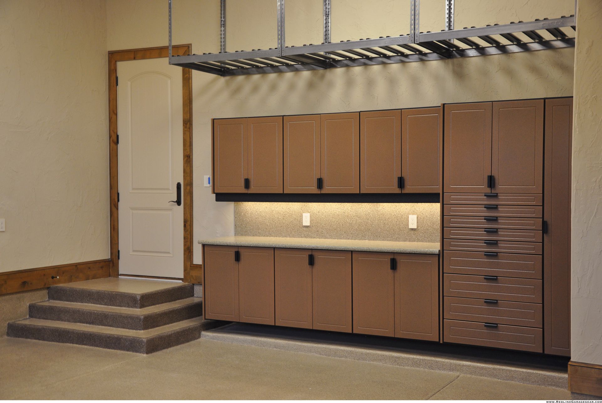 Storage cabinets and a lofted platform in a warehouse-like room with stairs and a closed door