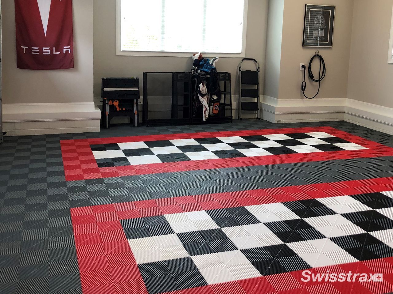 Indoor room with red, black, and white checkered rugs on the floor and wall-mounted gear in the background