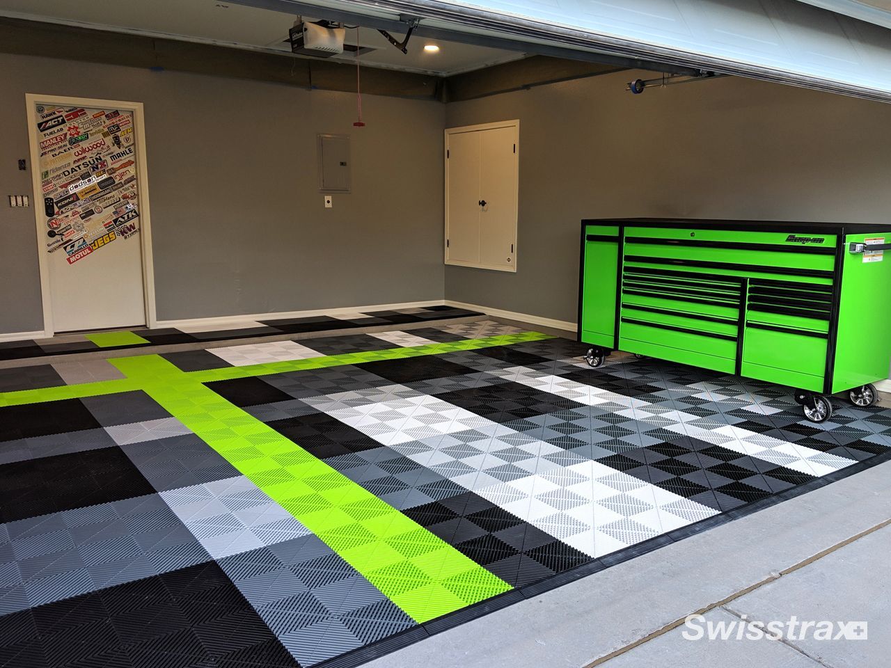 Garage with black, gray, and neon green floor tiles and a bright green tool chest on the right.