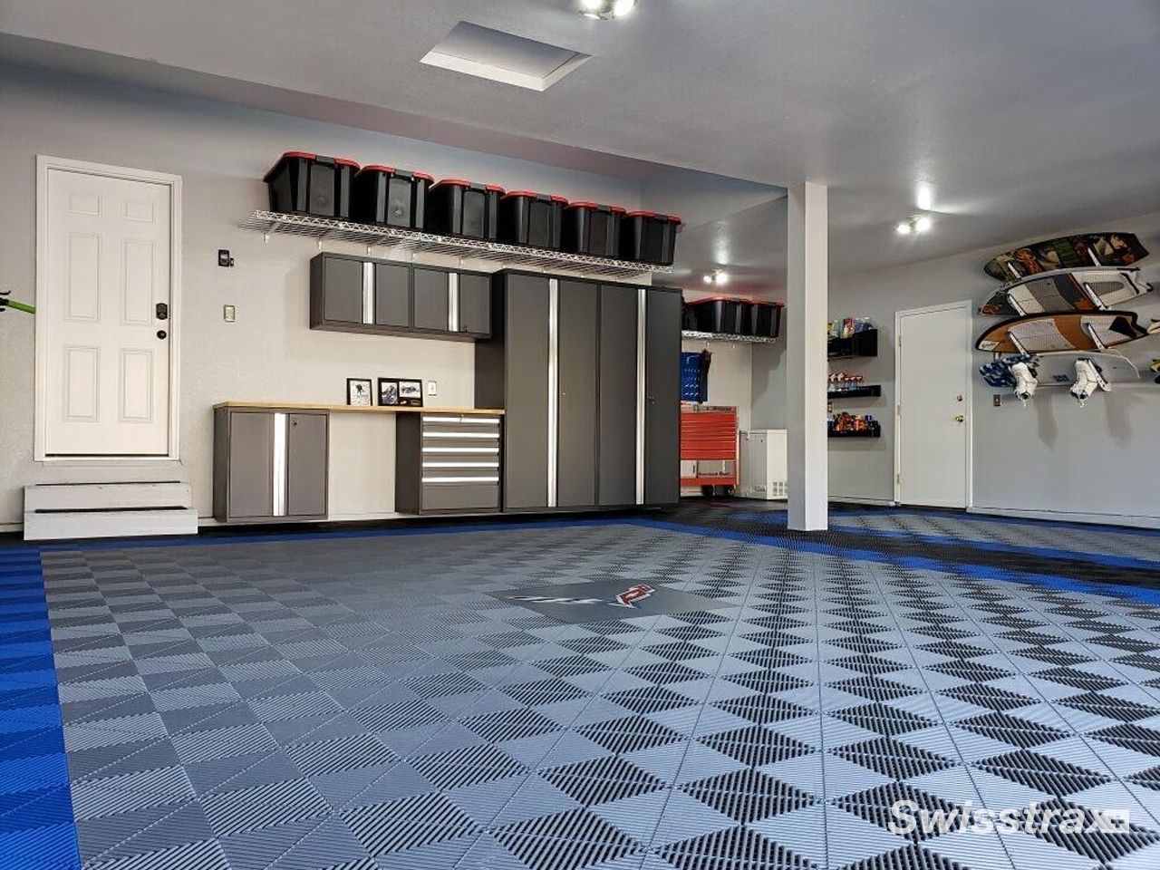 Garage interior with blue checkered floor, cabinets, storage shelves, and skateboards on the wall