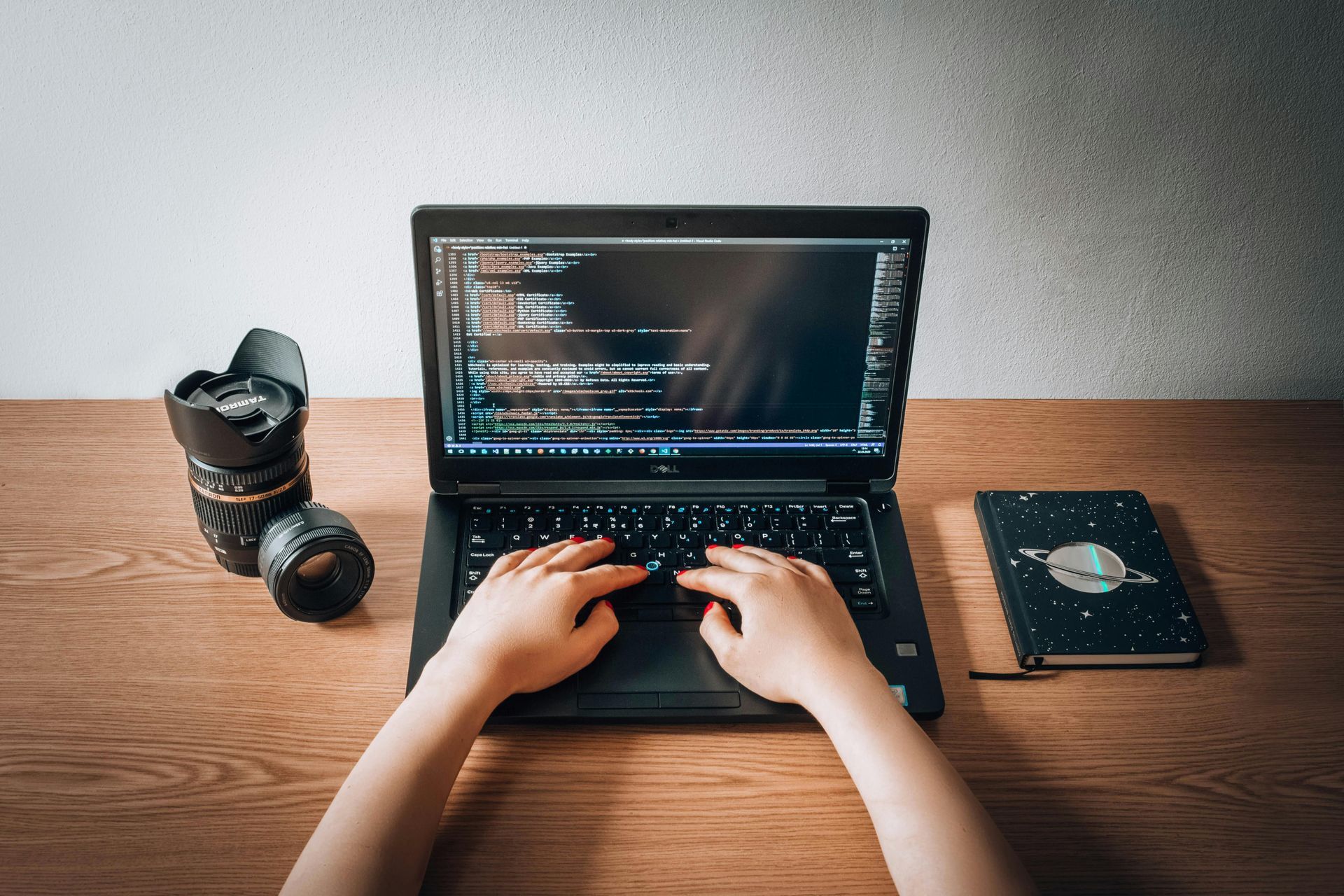 A person is typing on a laptop computer on a wooden desk.