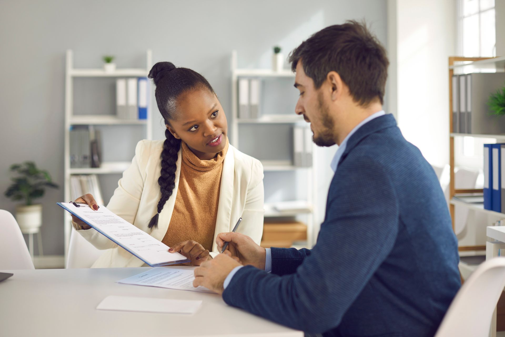 Two individuals discussing paperwork at a table in Homeland Title Settlement Agency, title company i