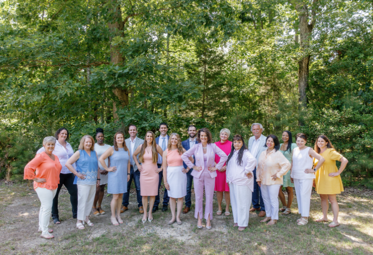 A group of people are posing for a picture in front of trees.