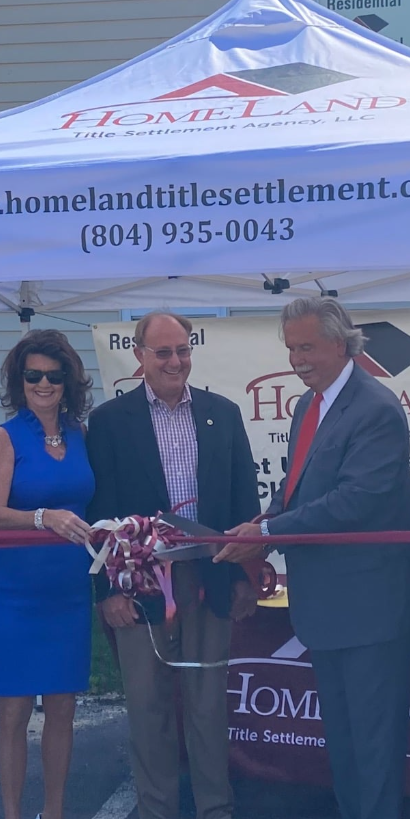 A man in a suit is cutting a red ribbon in front of a tent.