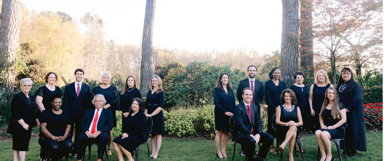 A group of people are posing for a picture in front of trees.