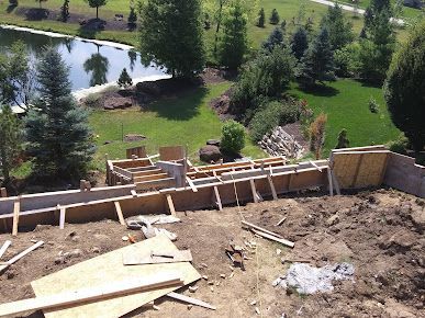 A building is being built on top of a dirt hill next to a lake.