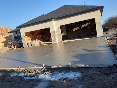 A house under construction with a concrete driveway in front of it.