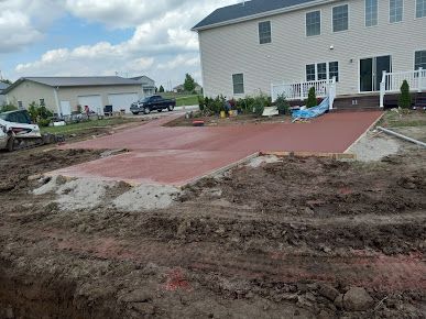A concrete driveway is being built in front of a large house.
