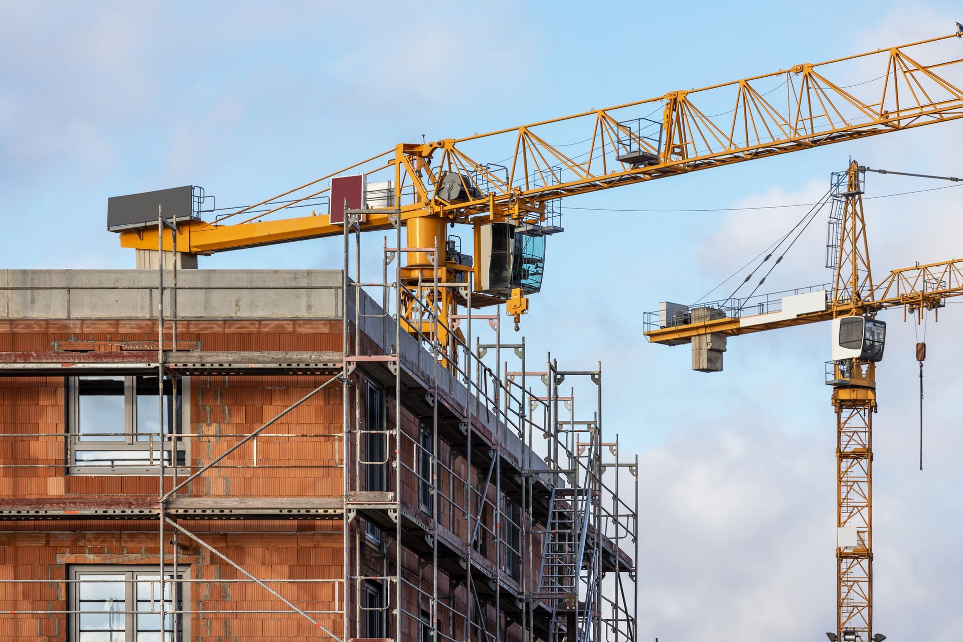 Construction site of a residential building with scaffolding and large cranes