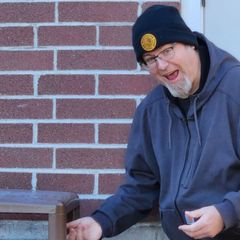 a man wearing a black hat with a yellow patch on it