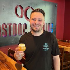 a man in a red jacket is holding a mug of beer