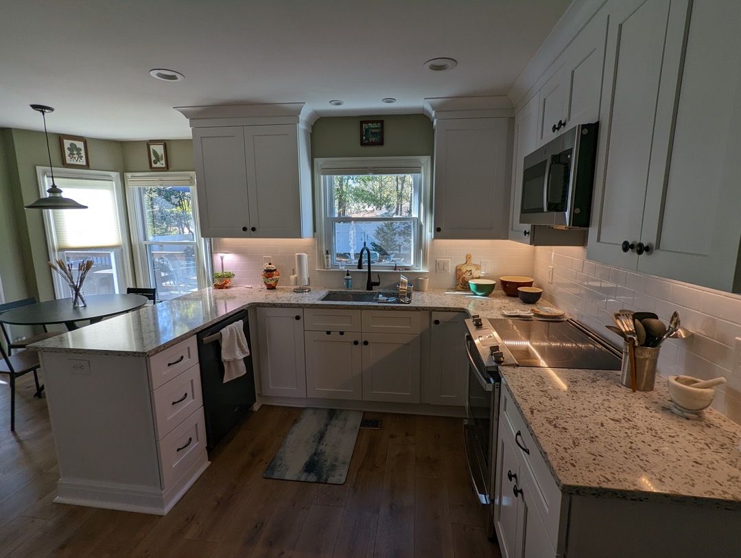 A kitchen with white cabinets , granite counter tops , stainless steel appliances and a large island.