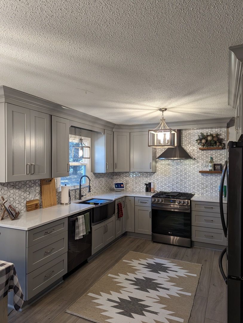 A kitchen with gray cabinets , stainless steel appliances , a rug and a stove.