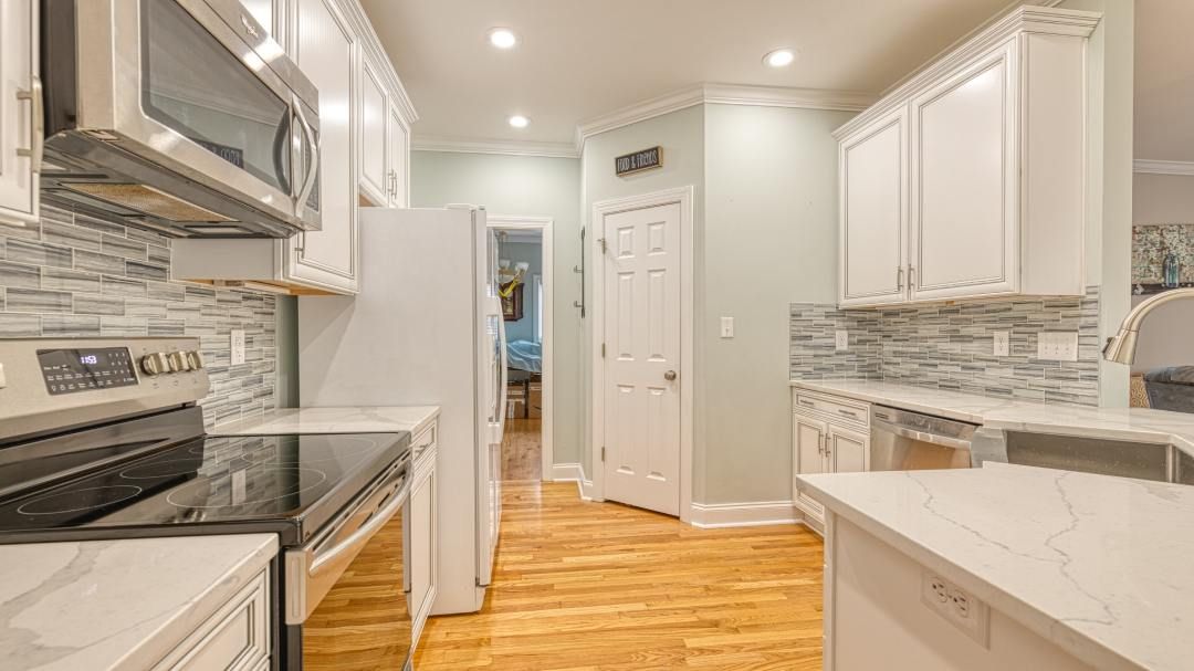 A kitchen with white cabinets , stainless steel appliances , and hardwood floors.