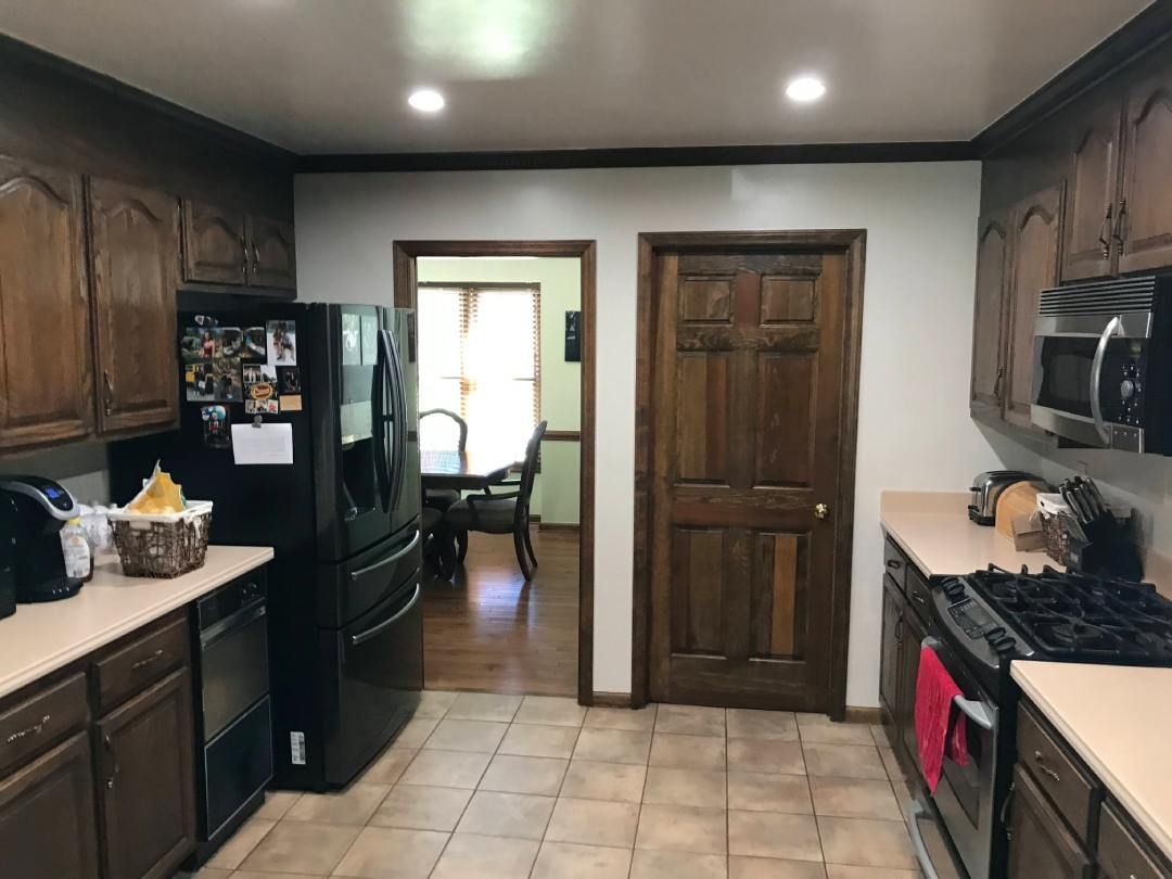 A kitchen with brown cabinets and a black refrigerator