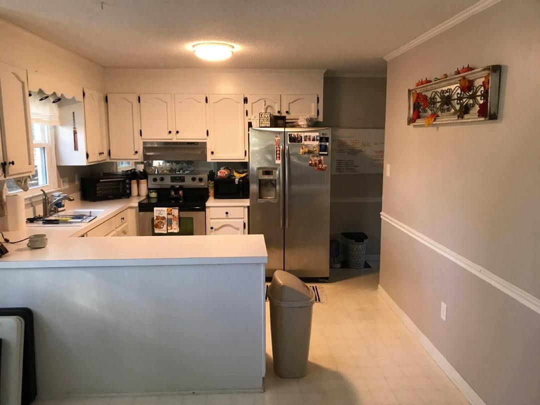 A kitchen with white cabinets and a stainless steel refrigerator