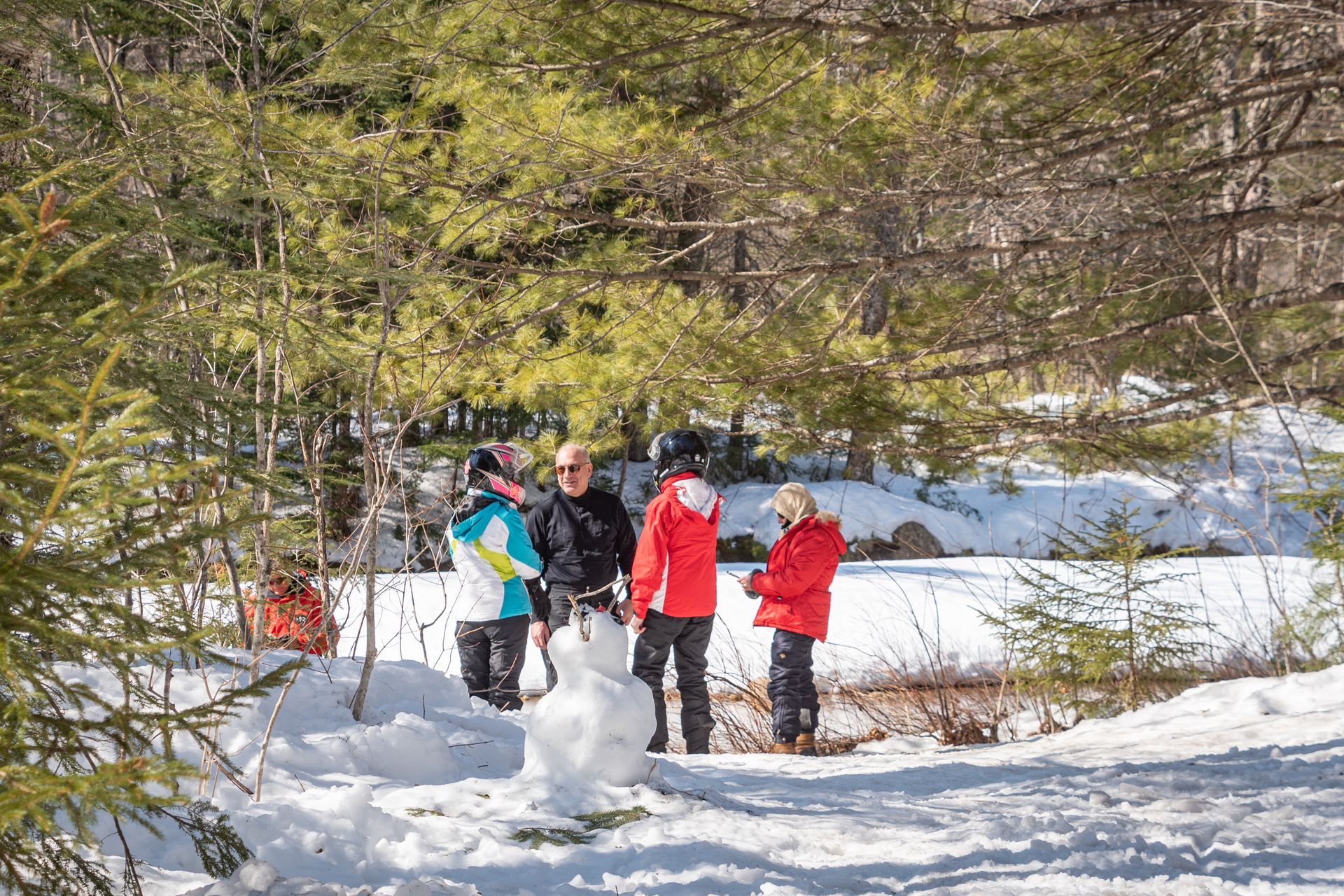 a group of people standing in the snow looking at a snowman