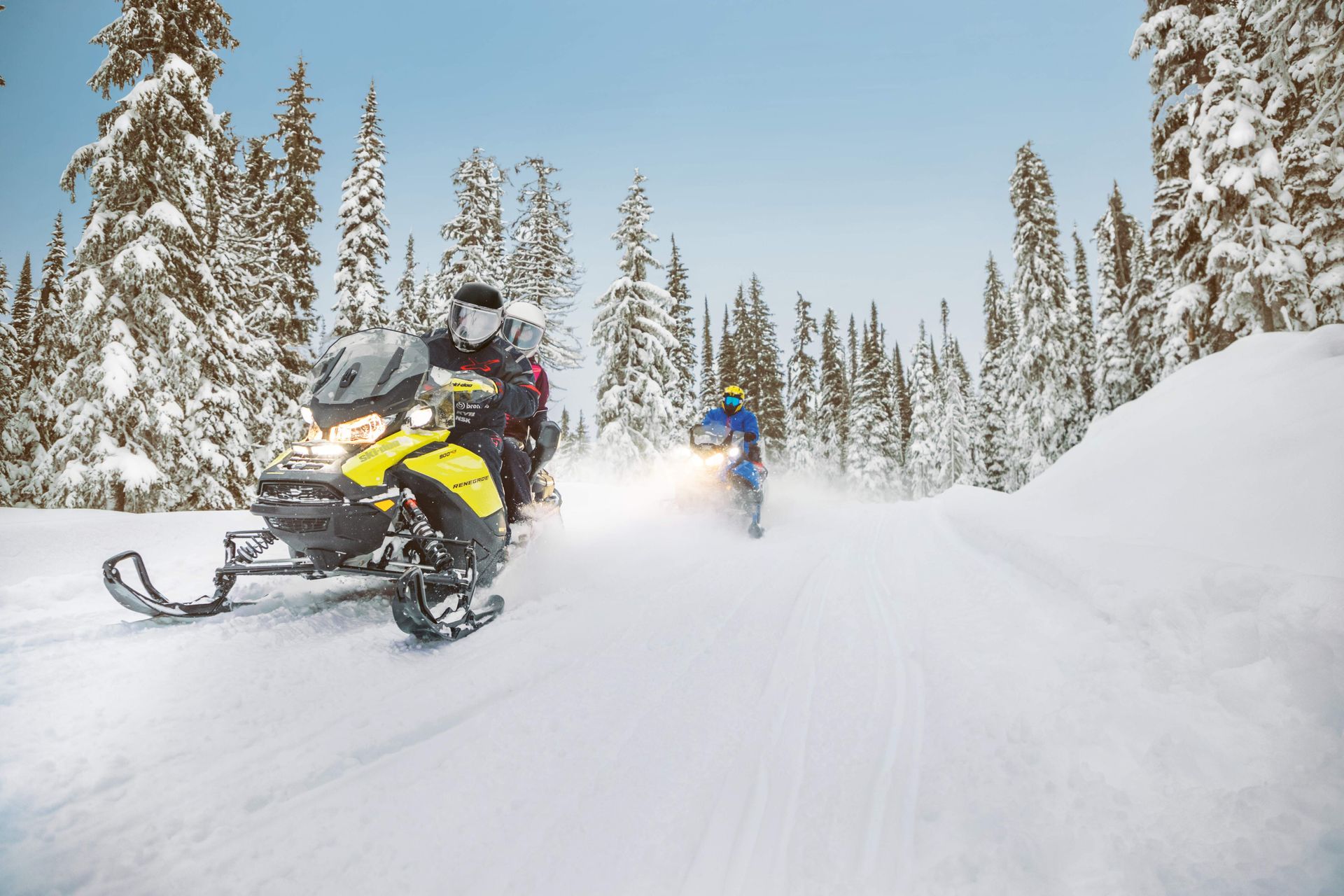 a man riding a yellow and black snowmobile in the snow