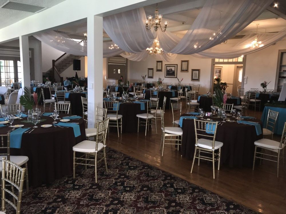 A large room with tables and chairs set up for a wedding reception