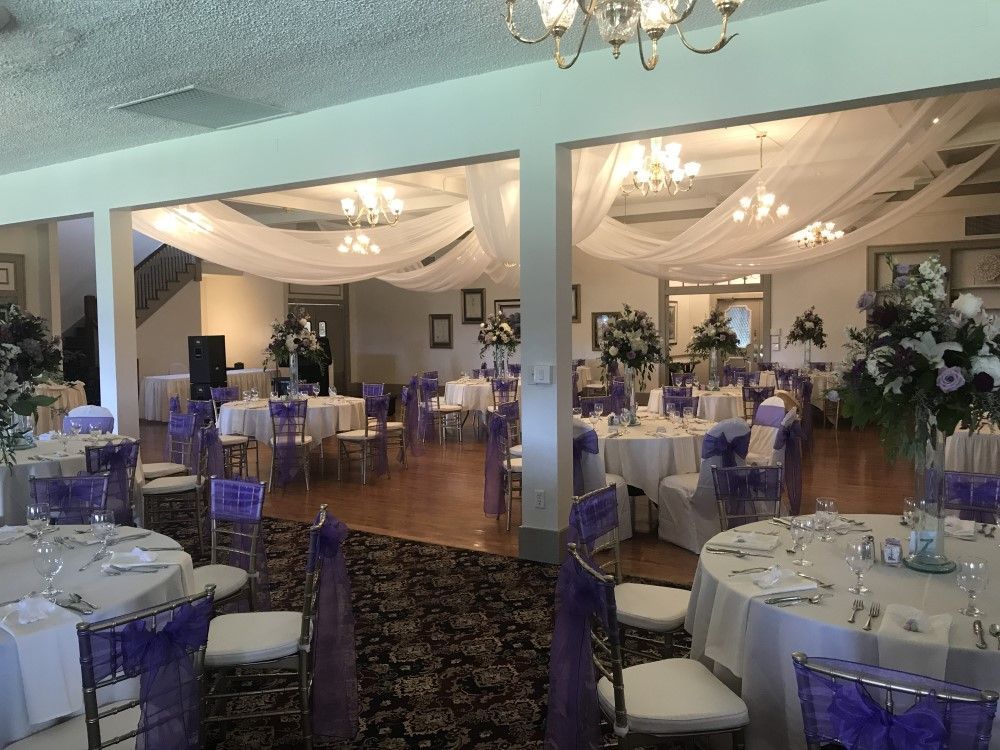 A large room with tables and chairs set up for a wedding reception.