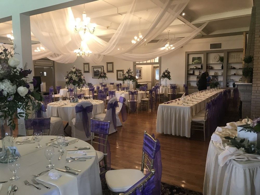 A large room with tables and chairs set up for a wedding reception.