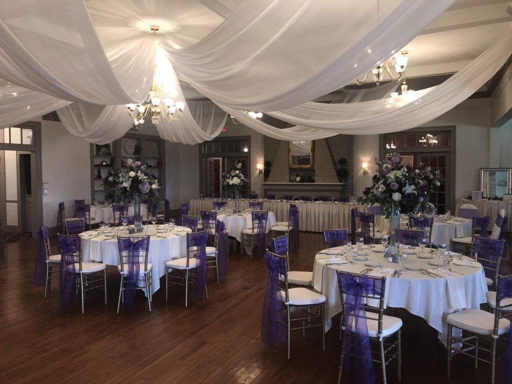 A large room with tables and chairs set up for a wedding reception.