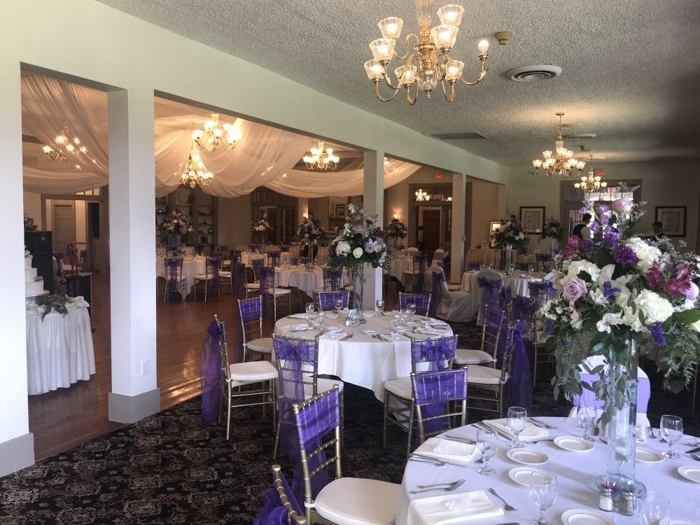 A large room with tables and chairs set up for a wedding reception.