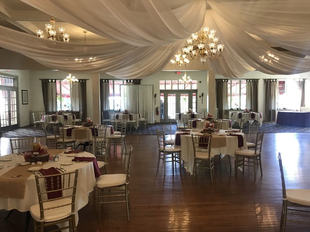 A large room with tables and chairs set up for a wedding reception.