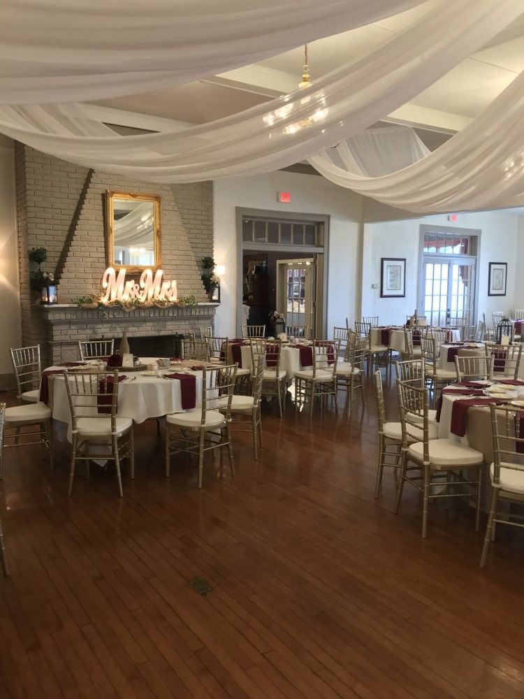 A large room with tables and chairs set up for a wedding reception.