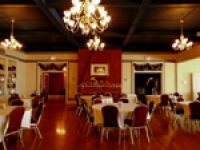 A dining room with tables and chairs and a chandelier hanging from the ceiling.