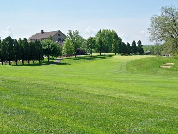 A golf course with trees and a house in the background