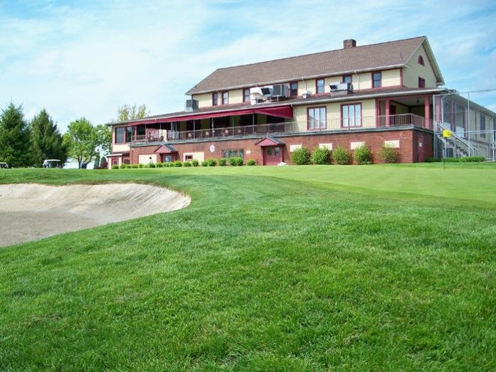 A large house is sitting on top of a lush green field.