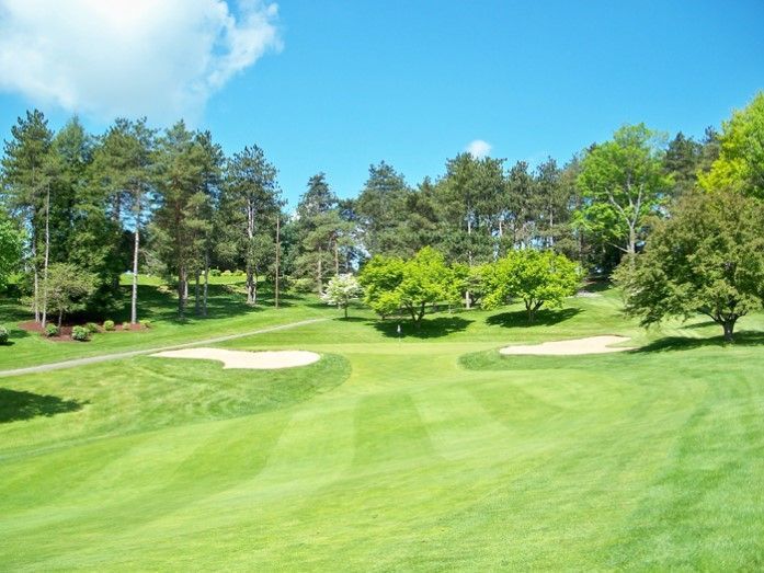A golf course surrounded by trees on a sunny day