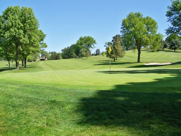 A golf course with a yellow flag on the green