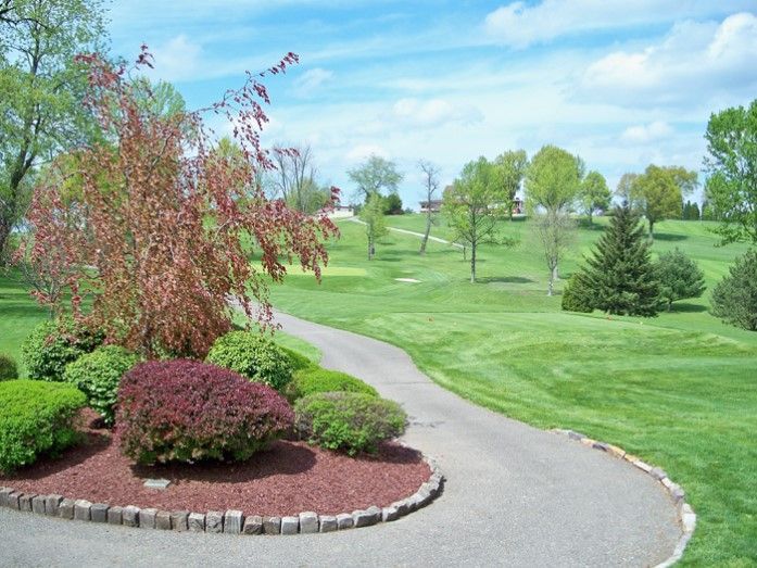 A path leading to a golf course with trees and bushes