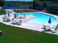A large swimming pool with tables and chairs around it.