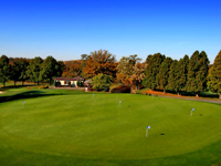 An aerial view of a golf course with a house in the background.