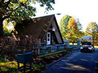 A golf cart is parked in front of a small house.