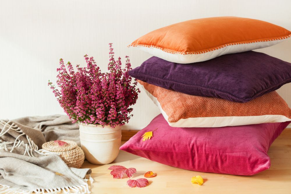 A Stack Of Colourful Pillows With A Vase Of Flowers — InHouse Homewares in Forster, NSW
