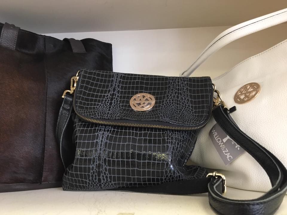 A Woman Is Holding A Pink Flower And A Black Purse — InHouse Homewares in Forster, NSW