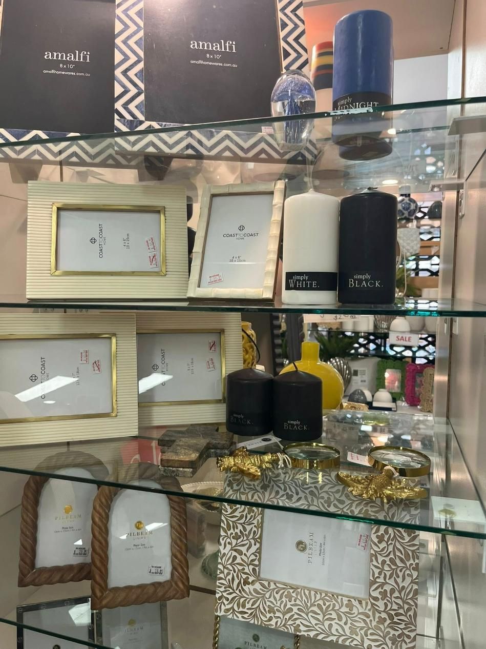 A Display Of Candles And Picture Frames On A Glass Shelf — InHouse Homewares in Forster, NSW