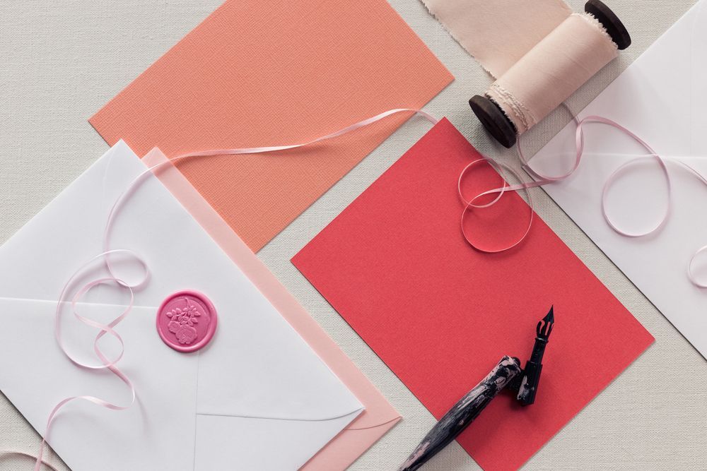 A White Envelope With A Pink Wax Seal Is Surrounded By Pink Papers And Ribbons — InHouse Homewares in Forster, NSW