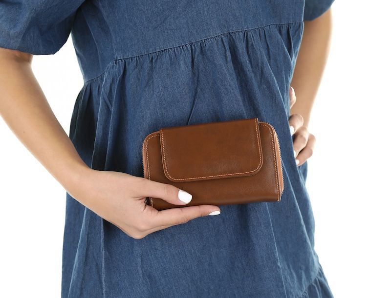 A woman in a blue dress is holding a brown leather wallet — InHouse Homewares in Forster, NSW