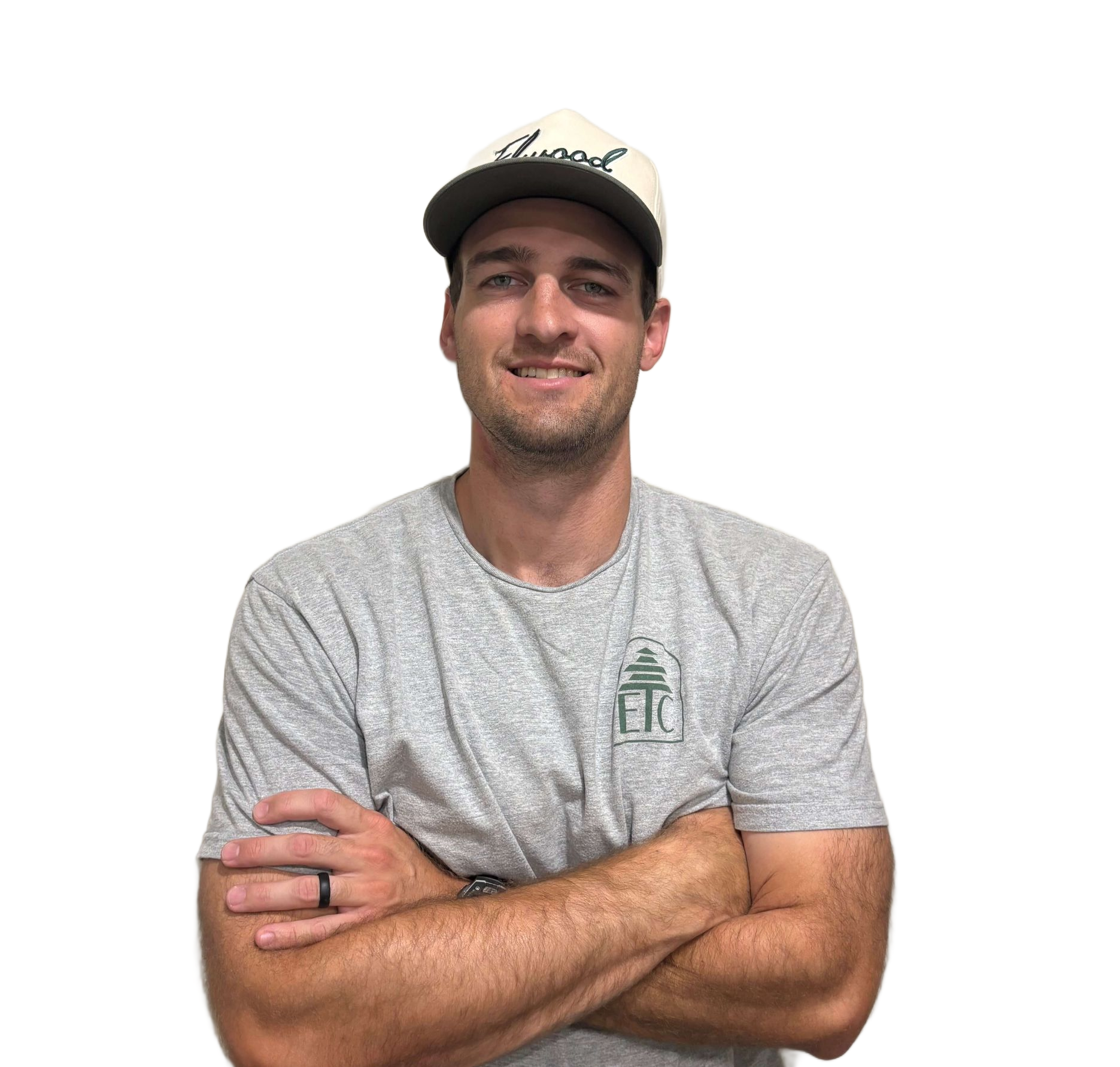 Man wearing cap and gray shirt with arms crossed, smiling at the camera.