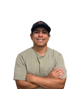 Man wearing a black cap and olive green shirt, arms crossed, smiling at the camera.