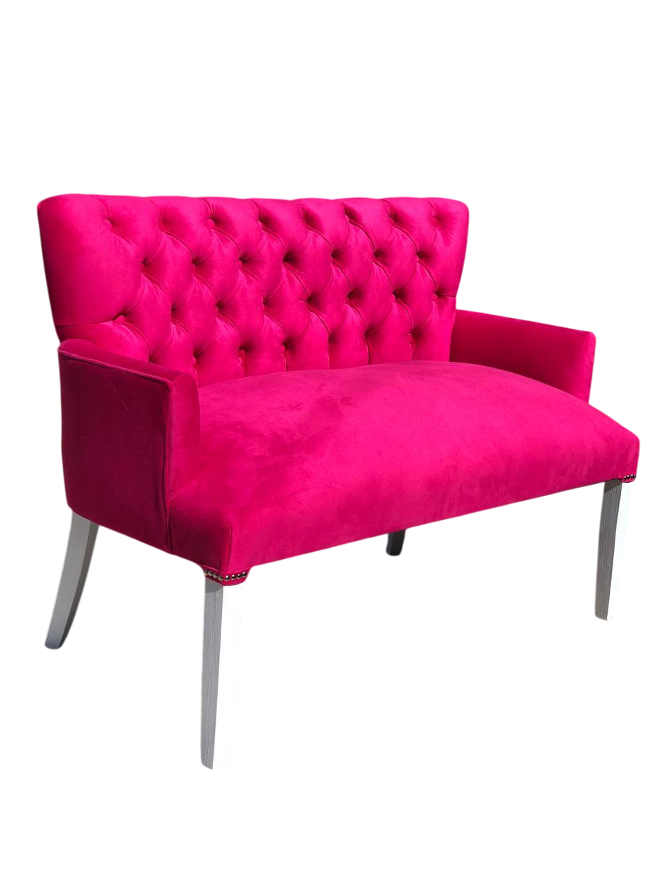 Sofá biplaza de terciopelo rosa fucsia con patas plateadas, vista en ángulo.