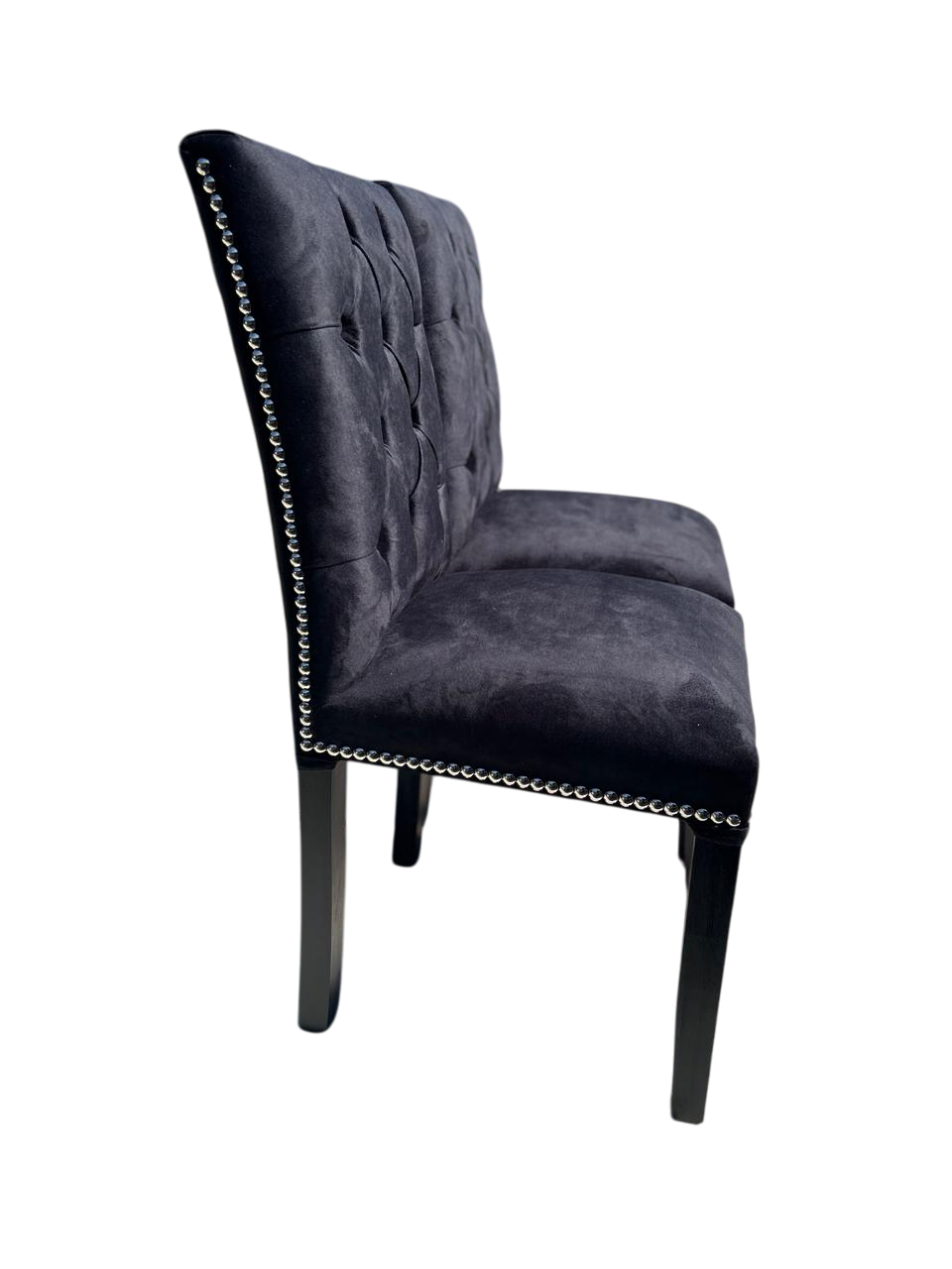 Dos sillas de comedor tapizadas en gris oscuro con capitoné y ribete de tachuelas plateadas.