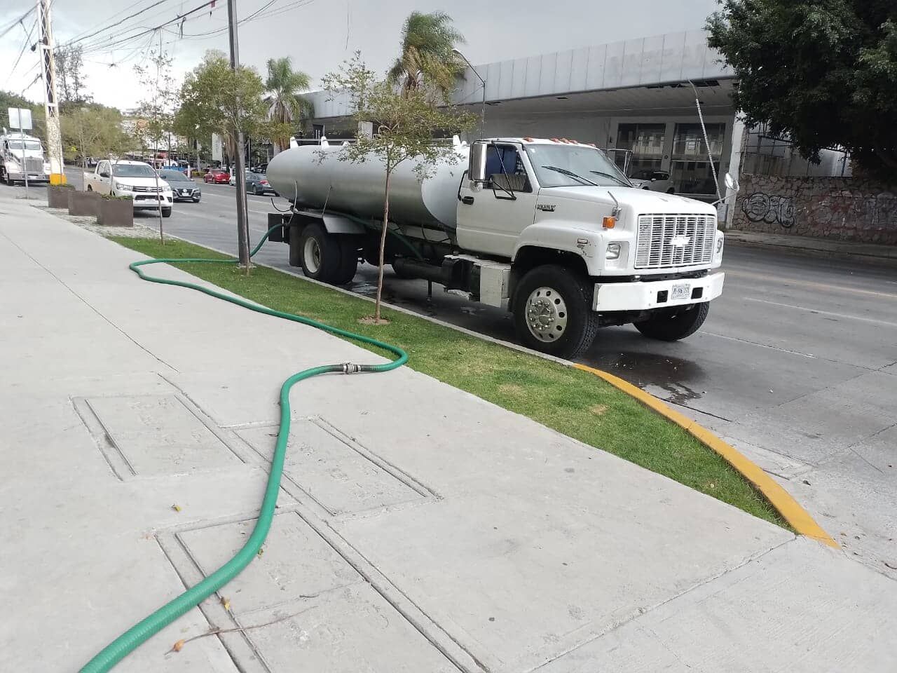 Un camión blanco con una manguera verde conectada a él.